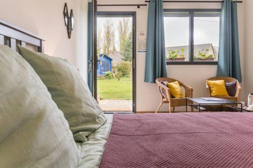 a bedroom with a bed and a table and windows at Entre terre et mer in Montfarville