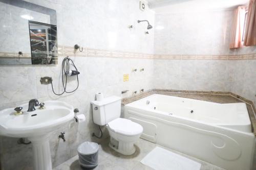 a bathroom with a toilet and a tub and a sink at Maison Florense Hotel in Sao Paulo