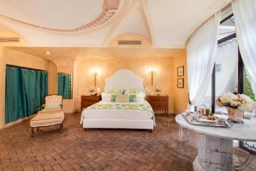 ein großes Schlafzimmer mit einem weißen Bett und einem Tisch in der Unterkunft Palazzo Marziale in Sorrent