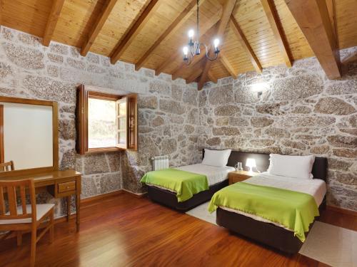 two beds in a room with a stone wall at Quinta do Bárrio - Manor Guest House in Terras de Bouro