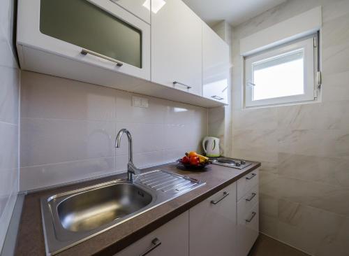 uma pequena cozinha com um lavatório e uma janela em Apartment Martina em Kaštela