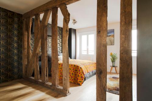 - une chambre avec un lit doté de poteaux en bois dans l'établissement Le Marais Calme et lumineux, à Paris