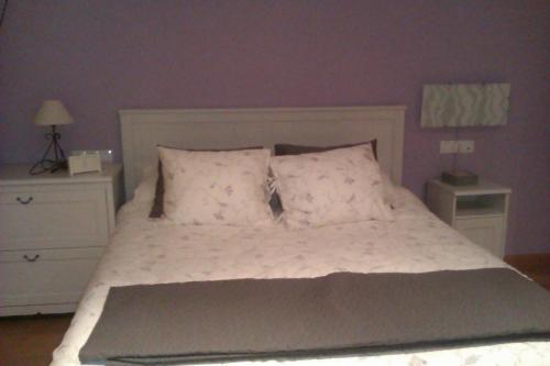 um quarto com uma cama com lençóis brancos e almofadas em APARTAMENTO EN CAMPO DE GOLF em Cirueña