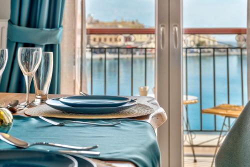 a table with plates and wine glasses on a balcony at Anaria Blue Suite in Ermoupoli