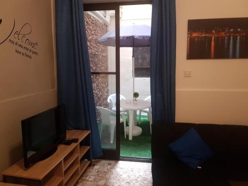a living room with a tv and a table and a window at Le Malte House St. Julians in St Julian's