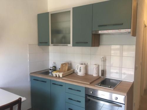 a kitchen with blue cabinets and a sink at RIVA Seafront holiday apartments in Rogoznica