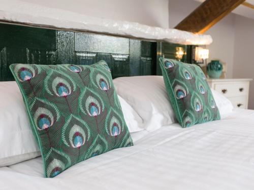 a bed with green and white pillows on it at Lancrigg in Grasmere
