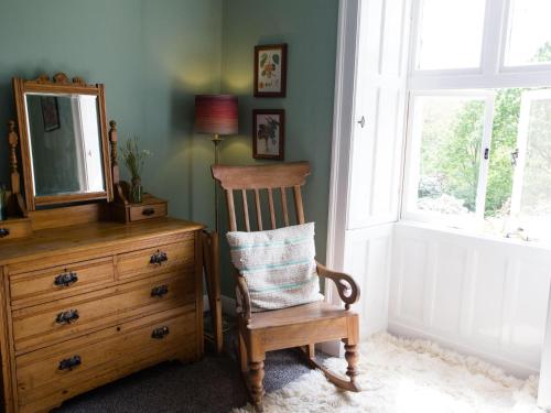a wooden chair sitting next to a dresser with a mirror at Lancrigg in Grasmere