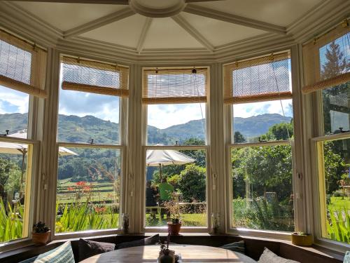 a room with large windows with mountains in the background at Lancrigg in Grasmere