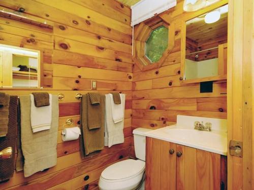 La salle de bains en bois est pourvue de toilettes et d'un lavabo. dans l'établissement Cedarwood Lodge, à Penfield