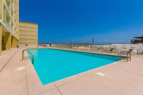 a swimming pool with chairs and a building at Boardwalk 983 in Gulf Shores
