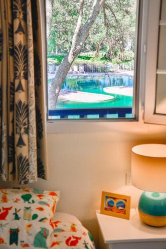 - une chambre avec une fenêtre offrant une vue sur la piscine dans l'établissement Cottage 40 **** Beach Golf Surf à pieds, à Moliets-et-Maa