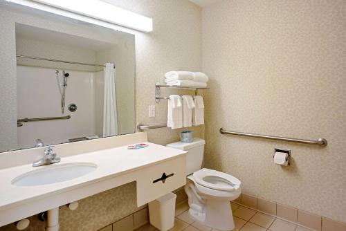 a bathroom with a toilet, sink and mirror at Quality Inn in Clinton