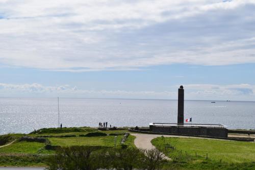 a group of people standing near the water with a lighthouse at Le Clos de la Pointe Saint-Mathieu in Plougonvelin