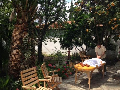 a man is laying on a table in a garden at Menelaos Apartments in Lefokastro