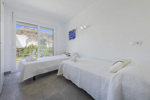 two beds in a white room with a window at Apartment Lauet in Port de Pollensa