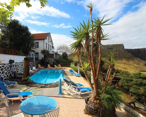 una piscina con sillas y una palmera junto a una casa en Quinta Do Canavial, en Velas