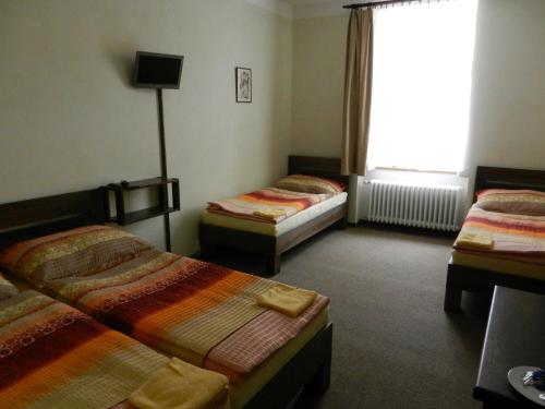 3 camas en una habitación con ventana en Hotel Beránek, en Blatná