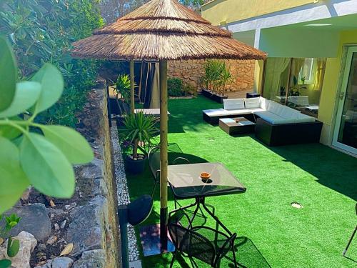 a patio with a table and a straw umbrella at Hotel Panoramico in Scauri