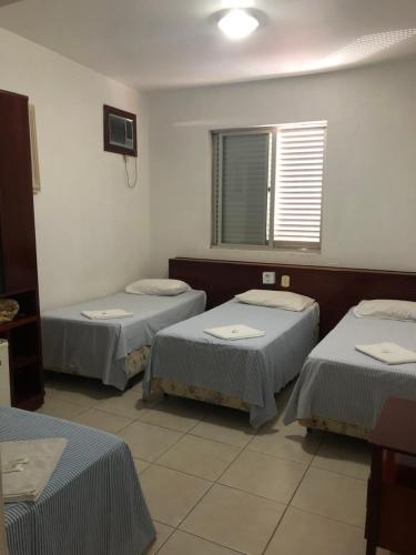 um quarto com três camas e uma janela em Vidagi Palace Hotel em Nova Serrana