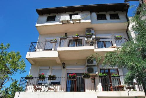a tall building with balconies and tables and chairs at Vila Delfin in Ohrid