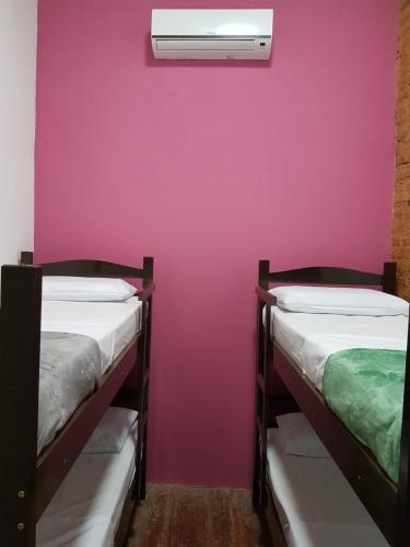 two bunk beds in a room with a pink wall at Hostel Casa de Avany in Cachoeira