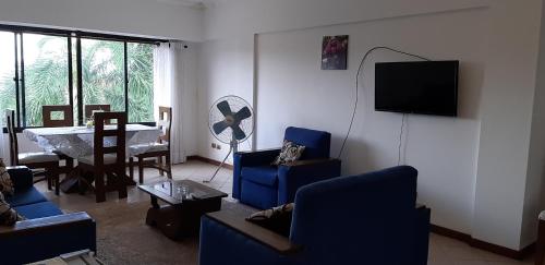 a living room with blue chairs and a television at Las Palmeras in Santa Cruz de la Sierra