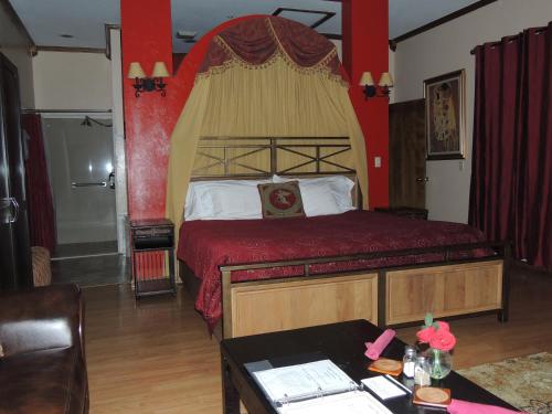 a bedroom with a large bed with a red wall at The Whispering Pines Inn in Norman