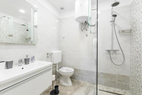 a white bathroom with a shower and a toilet at Apartment Mirella 1 "Your sunny sea-view escape with two terraces in the heart of Rabac" in Rabac