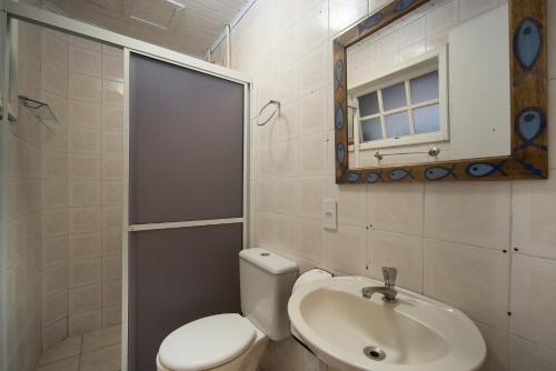 a bathroom with a toilet and a sink and a mirror at Pousada Treze Luas in Ilha do Mel