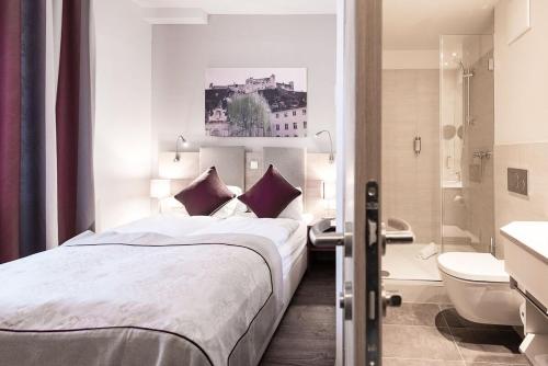 a hotel room with a bed and a bathroom at Hotel Das Junior by MAX 70 in Salzburg