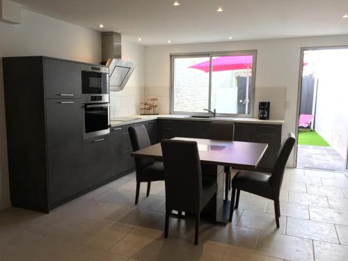 une cuisine avec une table et des chaises ainsi qu'une cuisine avec une cuisinière dans l'établissement Ma Ré Haute, à La Flotte