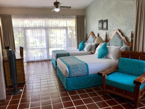 a bedroom with two beds and a couch and a tv at Hotel Posada Quinta Las Flores in Cuernavaca