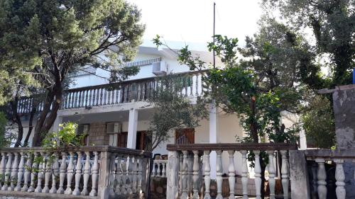 a white house with a white fence and trees at Apartmani Jovanovic in Lustica
