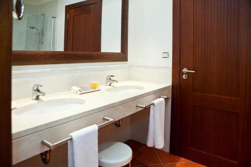 a bathroom with two sinks and a toilet and a mirror at Puerto Antilla Grand Hotel in Islantilla