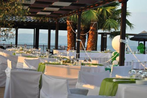 a restaurant with white tables and chairs and palm trees at Villa Eugenia in Theológos