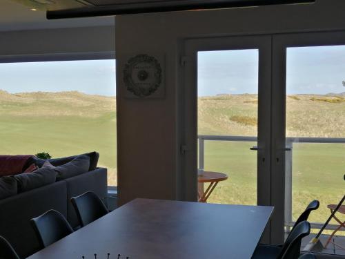 a room with a couch and a table and windows at Links Vista Portrush in Portrush