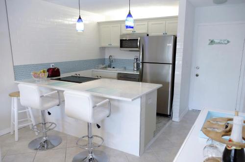 a kitchen with a refrigerator and a counter with stools at Beach Getaway - Ocean beach, tennis, golf, pool with tiki bar in Fort Pierce