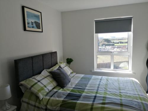 a bedroom with a bed with a plaid blanket and a window at Links Vista Portrush in Portrush