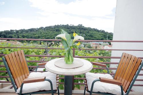 a table with a vase of flowers on a balcony at Apartments Ardura in Petrovac na Moru