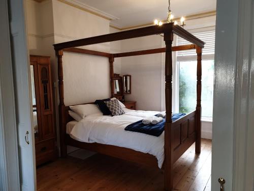 a wooden canopy bed in a room with a window at The Garden Apartment in Weymouth