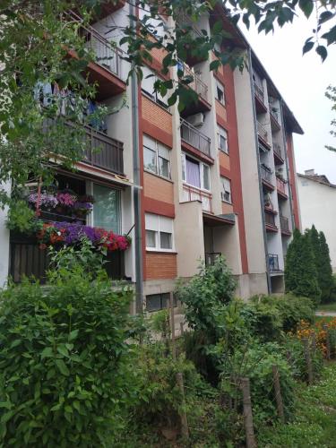 an apartment building with flowers in front of it at Apartman Ivan in Vrdnik