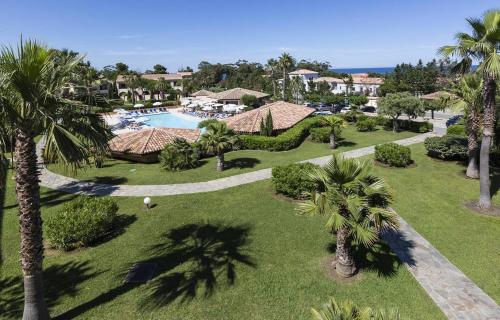 une vue aérienne d'un complexe avec piscine et palmiers dans l'établissement Sognu di Mare - Plage, piscine, farniente, à Linguizzetta