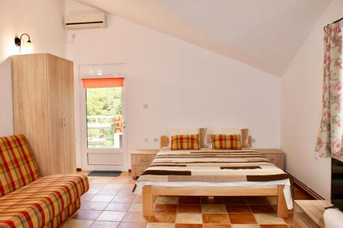 a bedroom with a bed and a couch and a window at Studio apartments Morinj in Donji Morinj