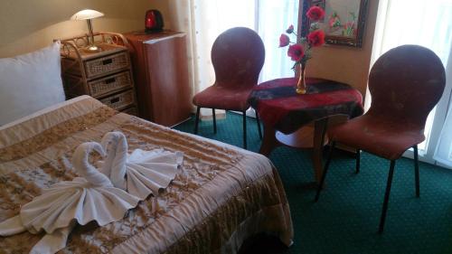 a hotel room with two swans on a bed and two chairs at Villa Europa in Mielno