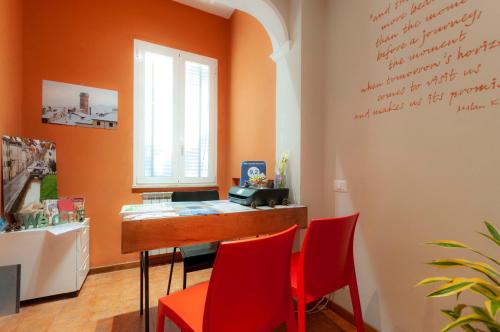una habitación naranja con un bar con sillas rojas en B&B Cento Passi Dalle Mura en Lucca