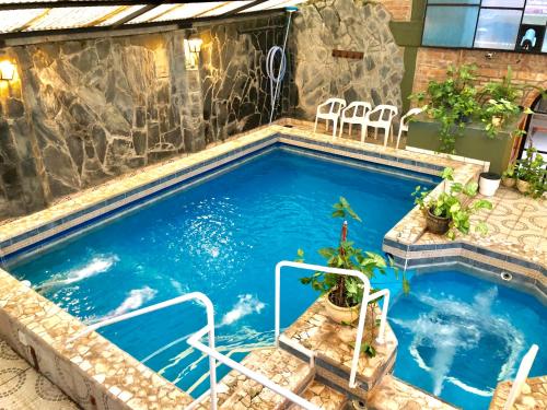 uma piscina com cadeiras e uma parede de pedra em Termas Del Sol em Termas de Río Hondo