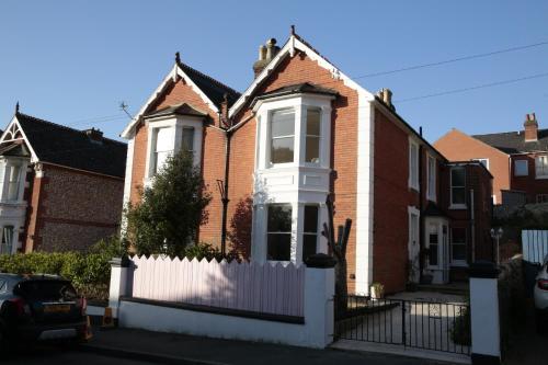 a red brick house with a white fence at The Pink Door Seaside Holiday Home in Ventnor