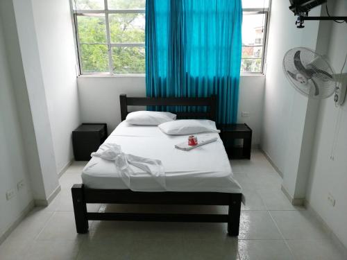 a small bedroom with a bed with a blue curtain at Hotel Ariari Azul in Villavicencio