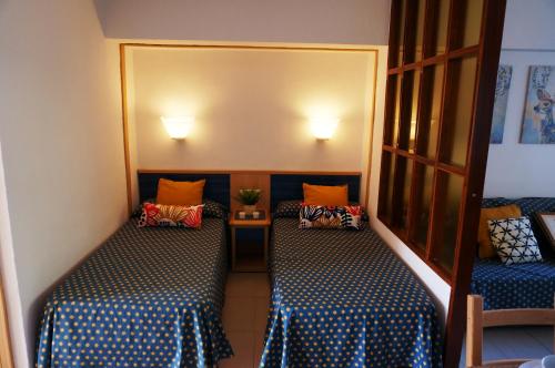 una piccola camera con due letti con cuscini blu e arancioni di Apartamento en Benalmádena a Benalmádena